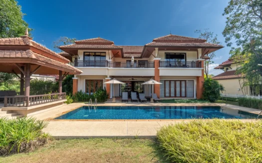 Двухэтажная вилла с голубым плиточным бассейном и шезлонгами