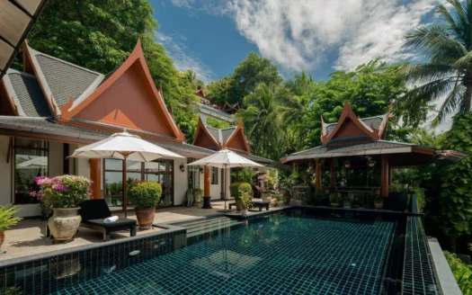 Вилла в тайском стиле у бассейна с зонтиками и тропическими растениями
