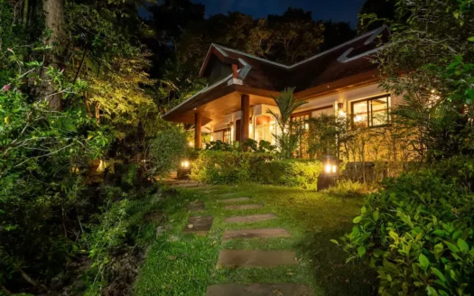 Ночной внешний вид деревянного бунгало с тёплым садовым освещением