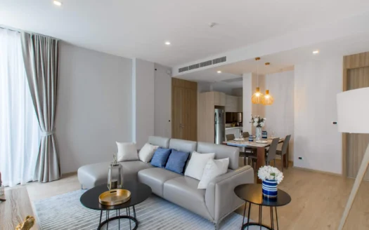 Светлая гостиная с серым угловым диваном и деревянной обеденной зоной