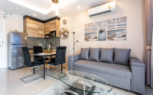 Открытая гостиная с серым диваном и стеклянным кофейным столиком