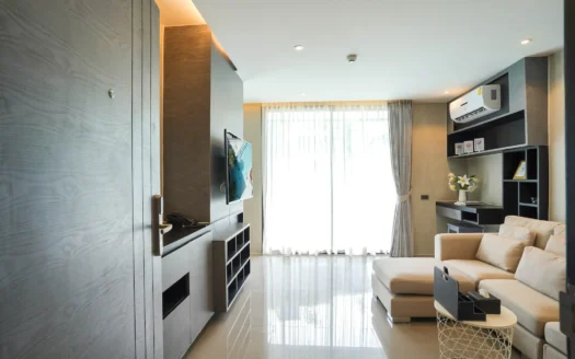 Светлая гостиная с телевизором на стене и кремовым диваном, большое окно