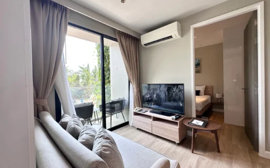 Гостиная с серым диваном, телевизором и видом на балкон