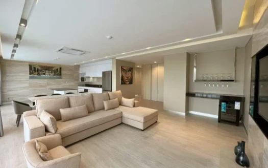 Просторная гостиная с бежевым угловым диваном и кухонным островом