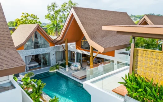 Воздушный вид на тропическую виллу с коричневыми крышами и бассейном
