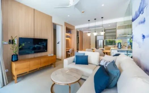 Гостиная с бежевым диваном, синими подушками, телевизор на деревянной стене