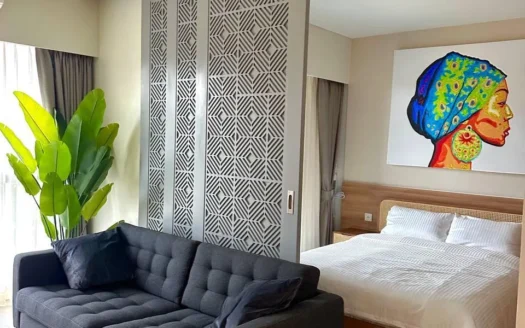 Темный серый диван с стеганой обивкой напротив геометрической перегородки в номере-люксе