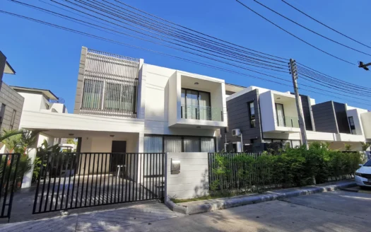 Современный белый фасад таунхауса с балконами и живой изгородью