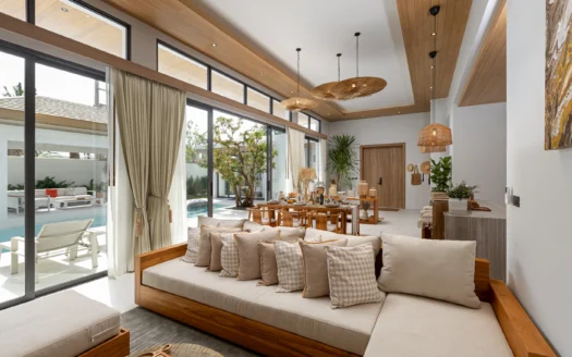 Освещённая солнечным светом гостиная с бежевым диваном и деревянным обеденным столом