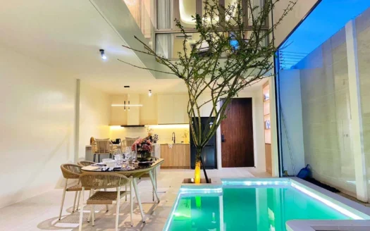 Внутренняя обеденная зона возле освещенного бассейна и высокого дерева