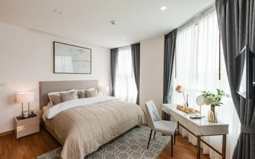 Яркая спальня с бежевой стеганой кроватью и белым столом у окон