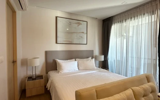 Гостевая спальня с белым бельём и бежевым диваном у окна