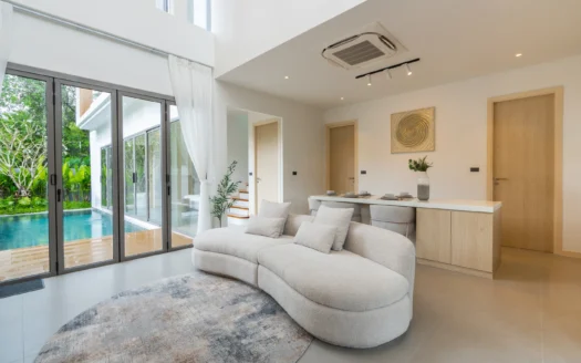 Освещенная гостиная с изогнутым бежевым диваном и стеклянными дверями