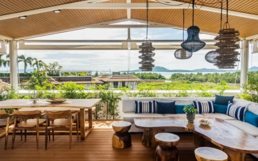 Открытая терраса с обеденным столом и синими подушками у воды