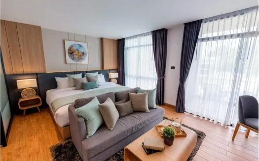 Спальня с большой кроватью, серым диваном и занавесками