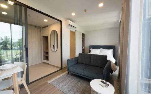 Яркая гостиная с синим диваном и кроватью, вид через стеклянную перегородку