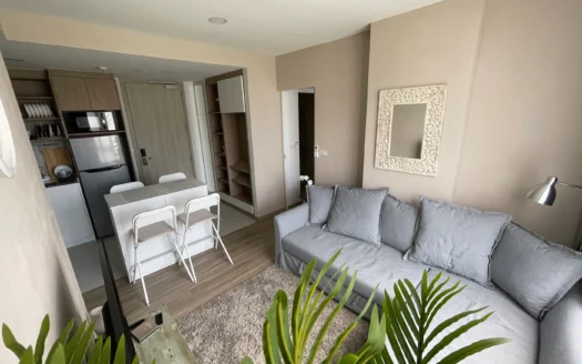 Гостиная с серым диваном, бежевыми стенами и белой резной рамой зеркала