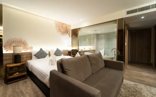 Гостевая комната с двуспальной кроватью, серым диваном, настенным солнцеподобным декором