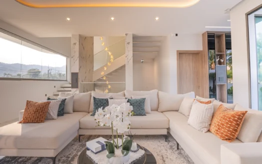 Светлая гостиная с угловым бежевым диваном и орхидеей на столике