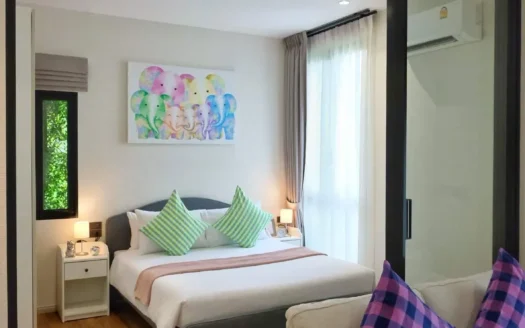 Спальня с двуспальной кроватью, зелёными полосатыми подушками, картина со слонами