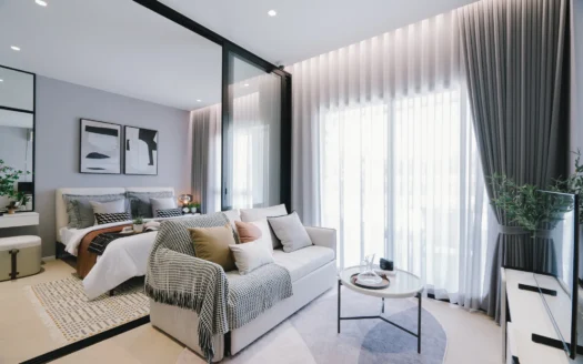 Современная спальня со серыми стенами, стеклянной перегородкой и диваном