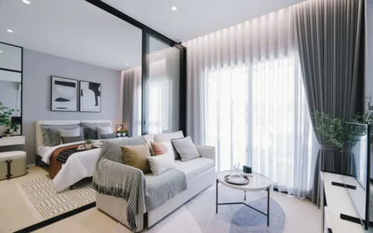 Гостиная с открытым планом и стеклянной перегородкой к спальне, серый диван