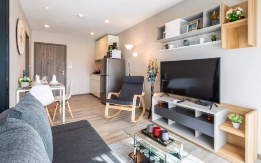 Современная гостиная с серым диваном, обеденным столиком и телевизором