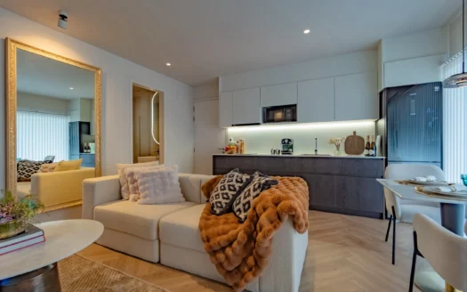 Открытая гостиная и кухня с кремовым диваном и меховым пледом