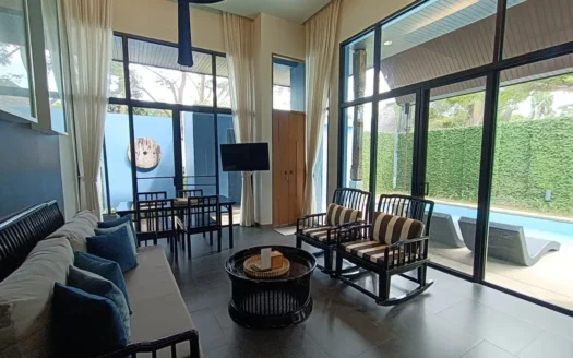 Просторная гостиная с белым диваном и синими подушками, стеклянные стены