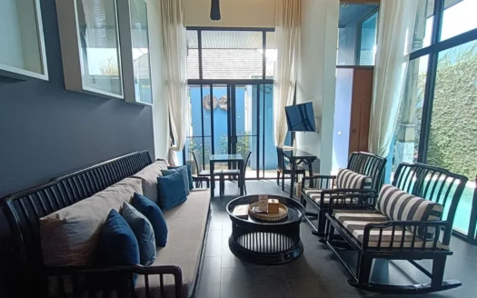 Яркая гостиная с темной деревянной мебелью, синими подушками и стеклянными окнами