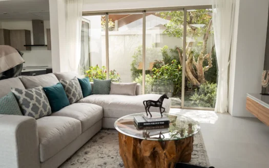 Светлая гостиная с бежевым диваном и большими стеклянными дверями в сад