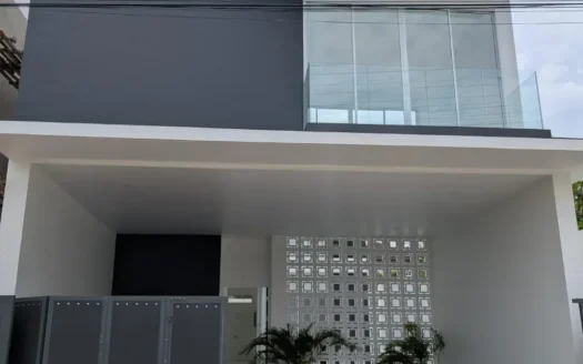 Современный двухэтажный дом с стеклянным балконом и воротами у подъезда