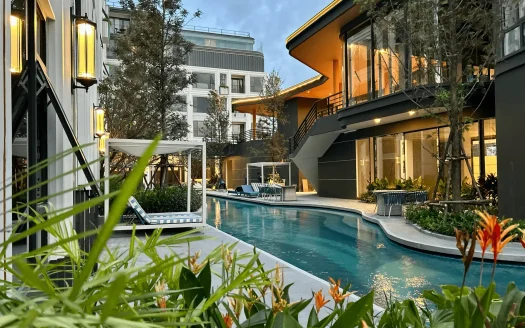 Изогнутый открытый бассейн с шезлонгами и тёплым освещением