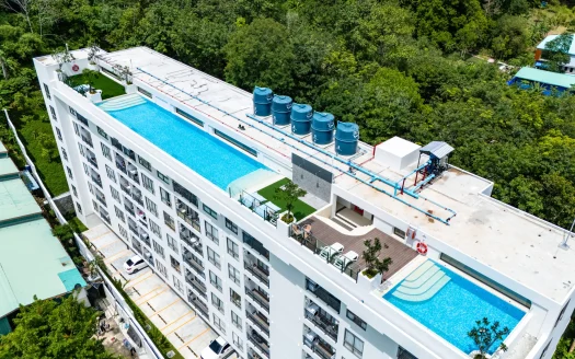 Воздушный вид на бассейн на крыше белого жилого здания и водонапорные баки