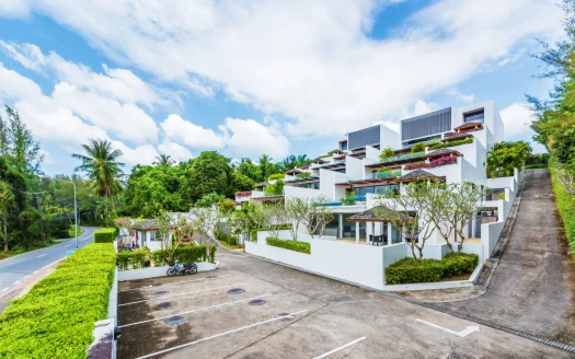 Террасированное белое здание с несколькими балконами и зеленью