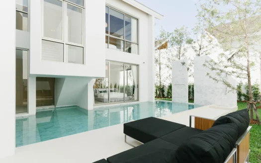 Белый современный особняк со стеклянными стенами и бирюзовым бассейном