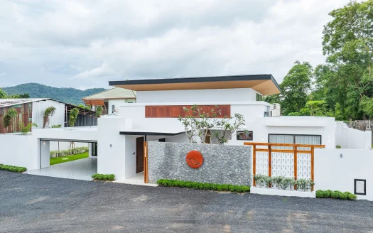 Современный белый дом с каменной стеной и оранжевой круговой эмблемой