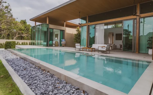 Современный фасад дома со стеклянными стенами и длинным бассейном