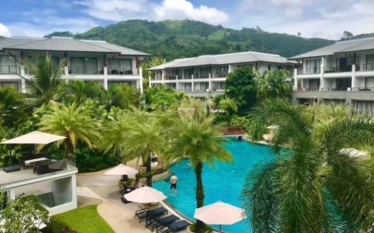 Бассейн курорта с пальмами и белыми зданиями днем