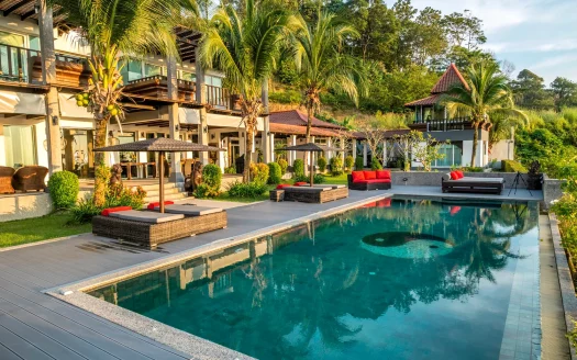 Солнечный курортный дворик с длинным синим бассейном и пальмовой террасой