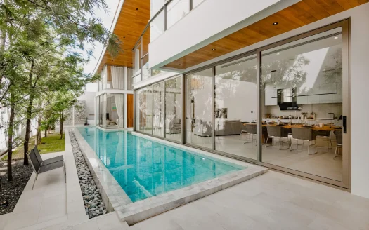 Стеклянный дом с длинным бассейном и уличной зоной отдыха