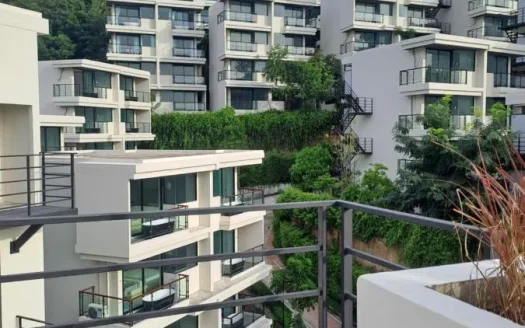 Балконный вид на белые современные жилые дома с зеленью на холме