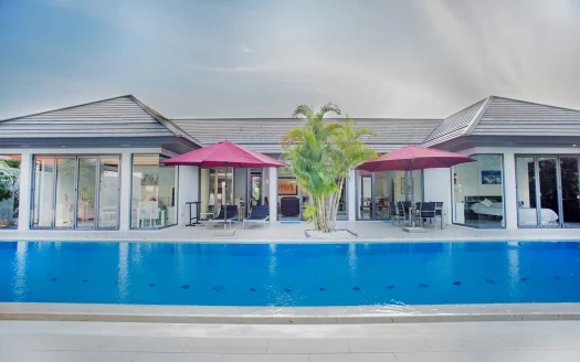 Экстерьер виллы с синим бассейном и красными зонтами