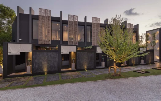 Двухэтажный черный фасад с решетчатыми панелями и стеклянными витринами на закате